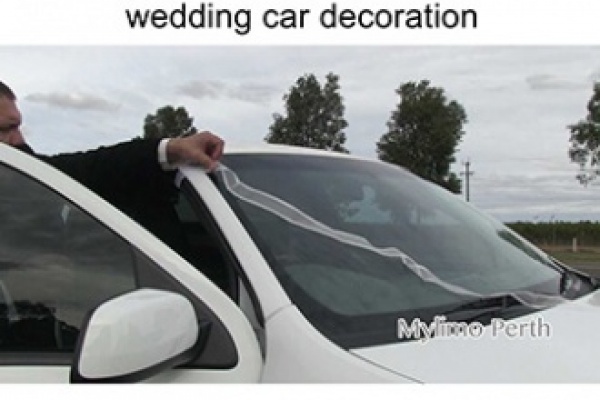 Mylimo chauffeur attaching a wedding ribbon to the wedding vehicle of choice